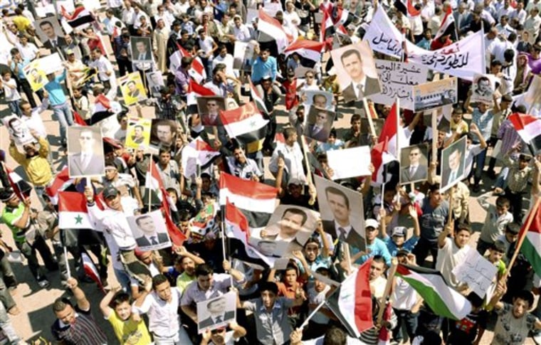 Syrian supporters of President Bashar Assad carry his pictures along national flags and banners during a rally in the northern city of Aleppo, Syria.